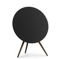 Profilansicht der Bang & Olufsen Beosound A9 in Black Anthracite aus einer Dreiviertel-Perspektive. Die Kombination aus schwarzem Textilbezug, anthrazitfarbenem Aluminiumring und Stativbeinen aus dunklem Nussbaumholz unterstreicht das elegante, maskuline Design. 