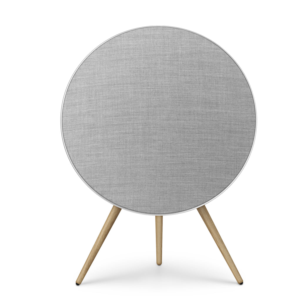Frontalansicht der Beosound A9 in Natural Aluminium. Der silberne Rahmen umschließt ein lichtgraues Textil-Cover, getragen von Stativbeinen aus heller Eiche. Ein Inbegriff für skandinavisches Design-HiFi.