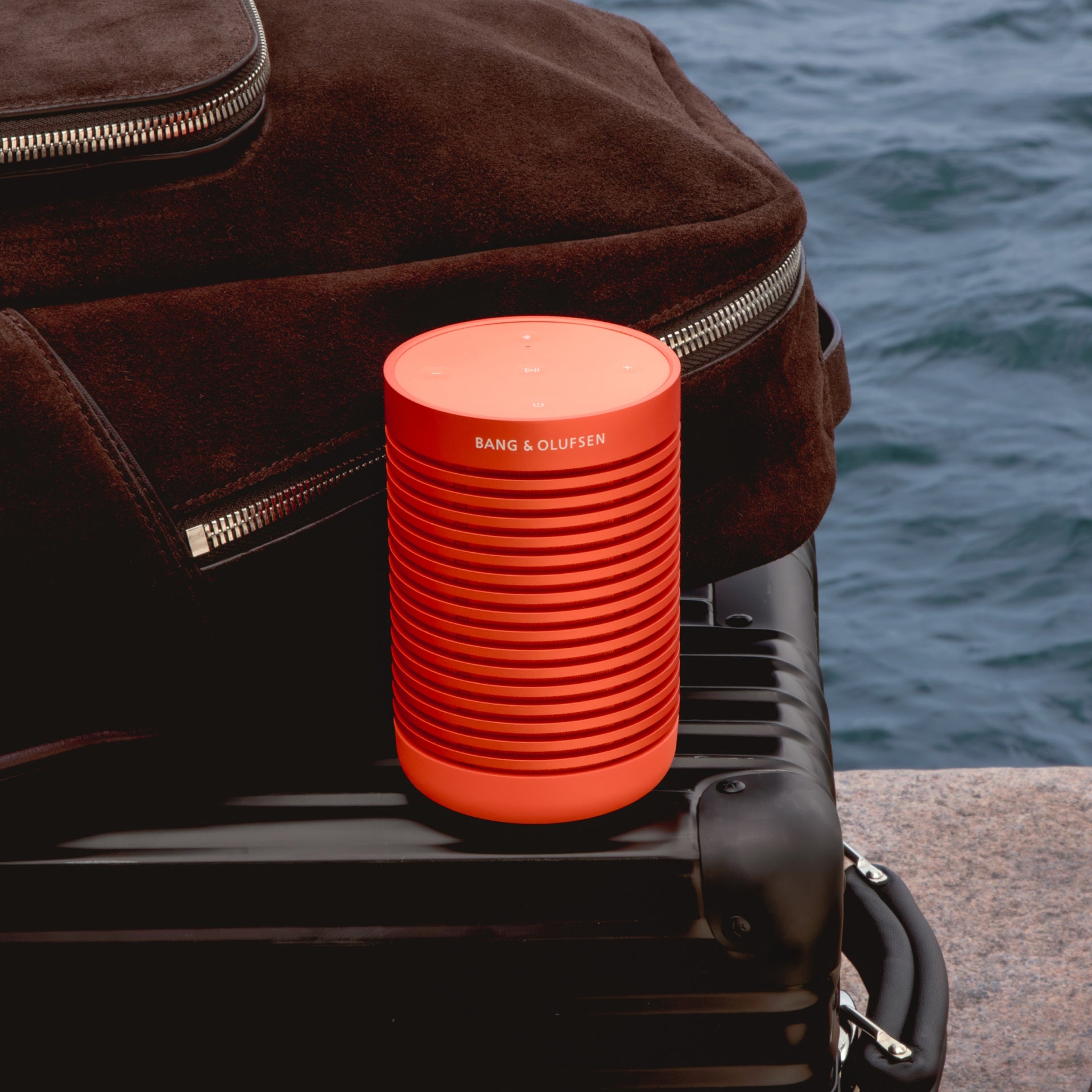 Beosound Explore in bonfire Ornage auf einem schwarzen Koffer