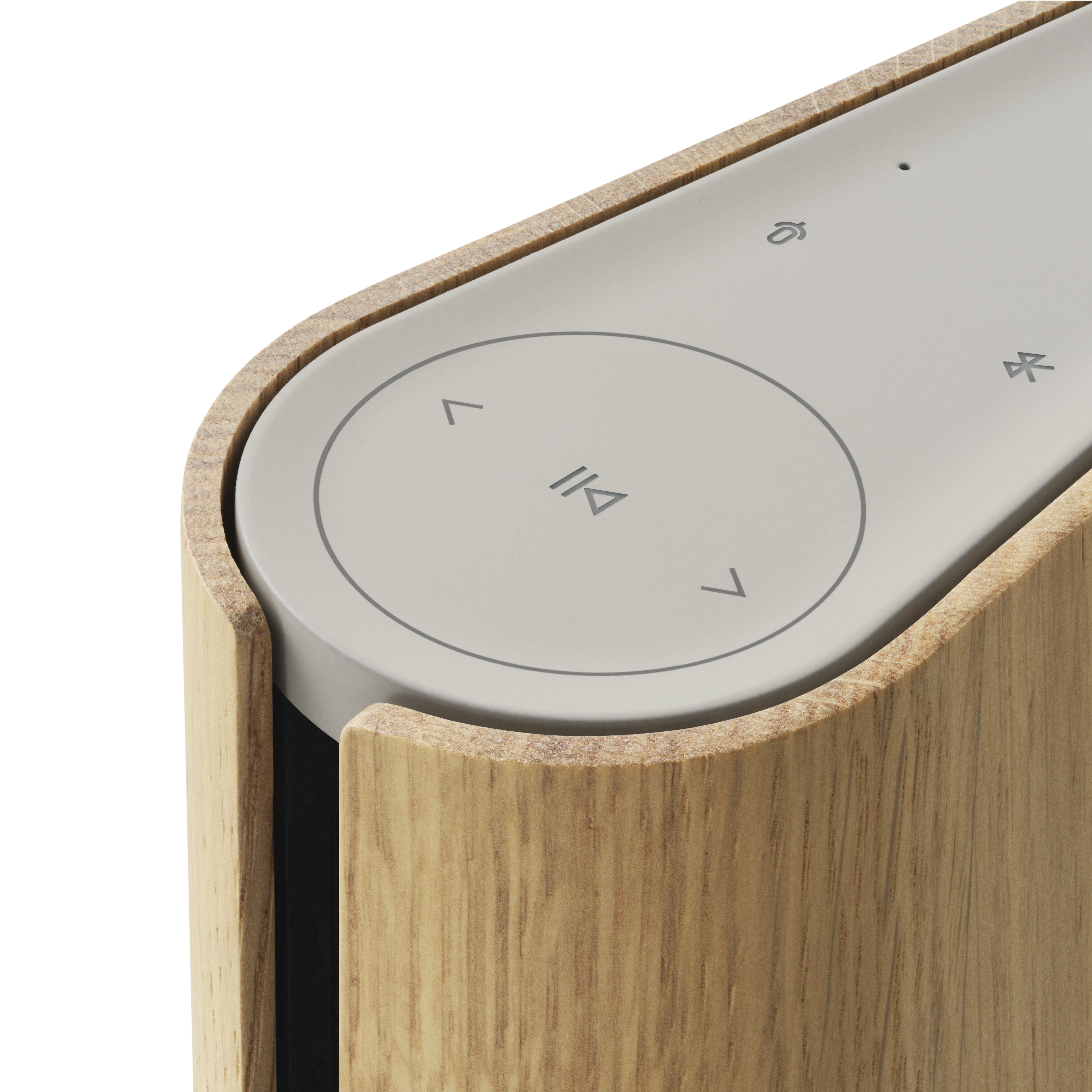 Detailaufnahme der Touch-Bedienoberfläche der Bang & Olufsen Beosound Emerge (Gold Tone / Light Oak). Zu sehen ist das minimalistische Interface mit Symbolen für Play/Pause, Lautstärke und Bluetooth, eingefasst in die markante, geschwungene Wange aus hellem Eichenholz.